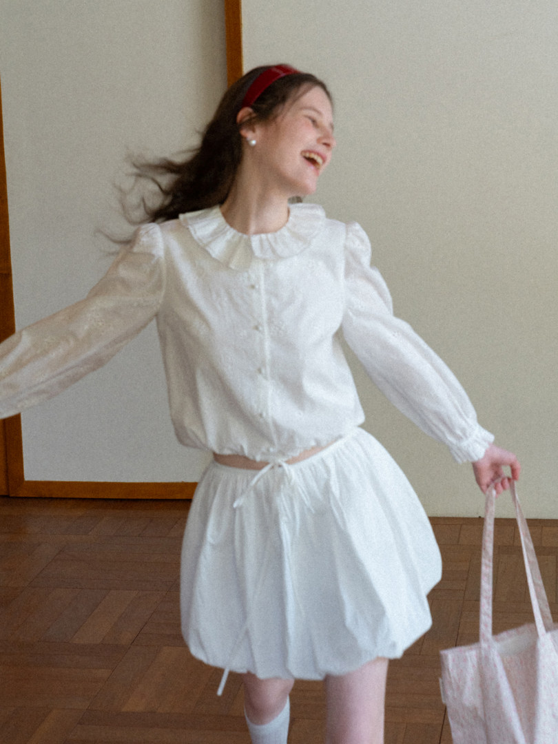 Woman wearing a white sheer blouse and matching skirt set