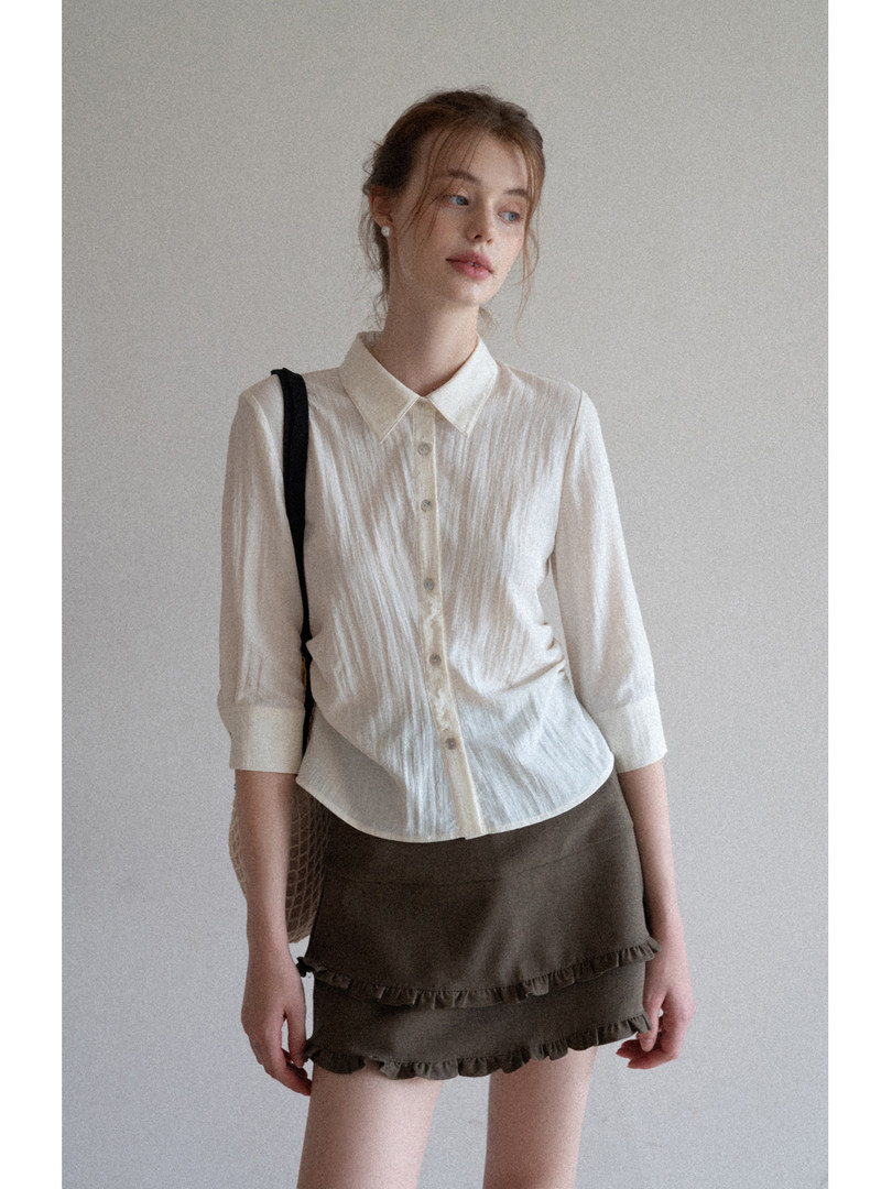 Model wearing a white button-up blouse with an olive ruffled mini skirt