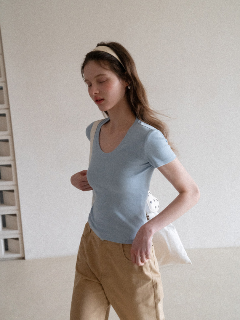 Woman wearing a light blue fitted short-sleeve top and tan pants