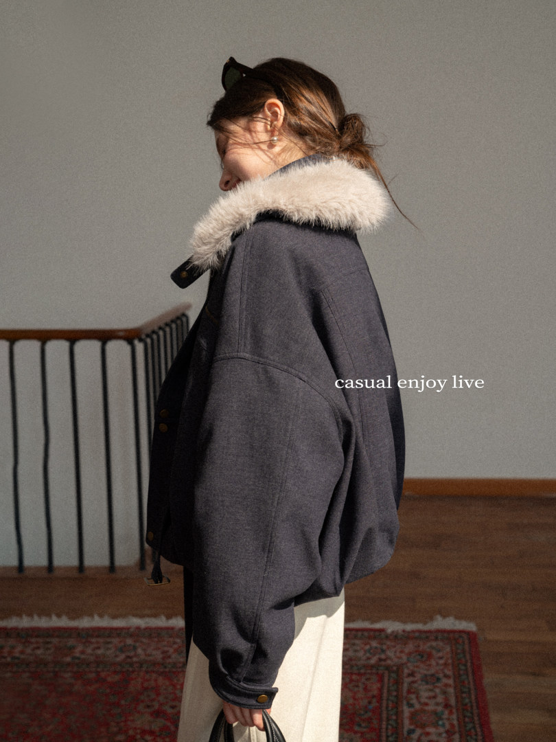 Model wearing a dark oversized coat with a fur collar