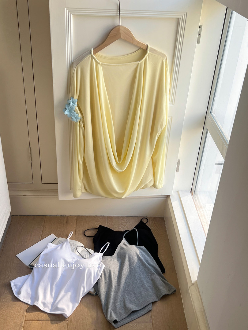 Assorted lightweight sleeveless tops and a draped yellow top hanging on a door