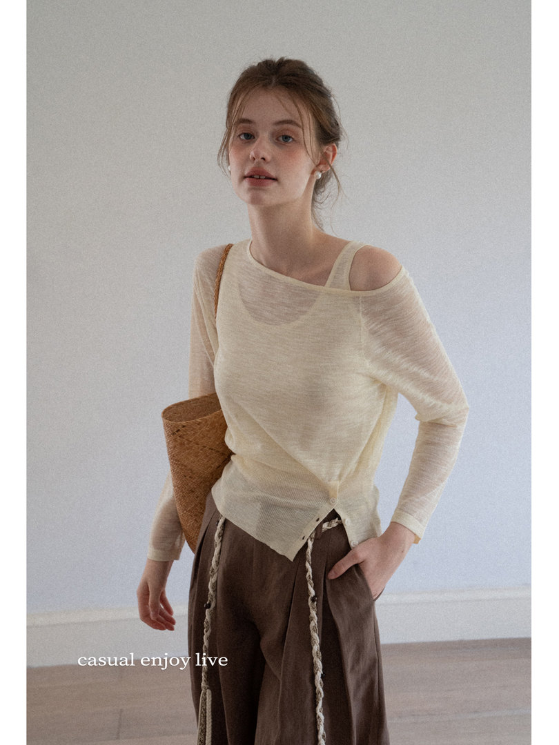 Model wearing a light cream sheer long-sleeve top with brown wide-leg pants and a woven bag