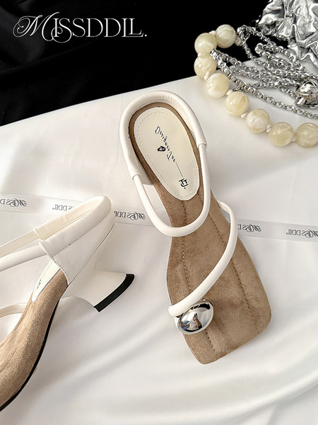 White heeled sandals with ankle straps and square heels on a white surface