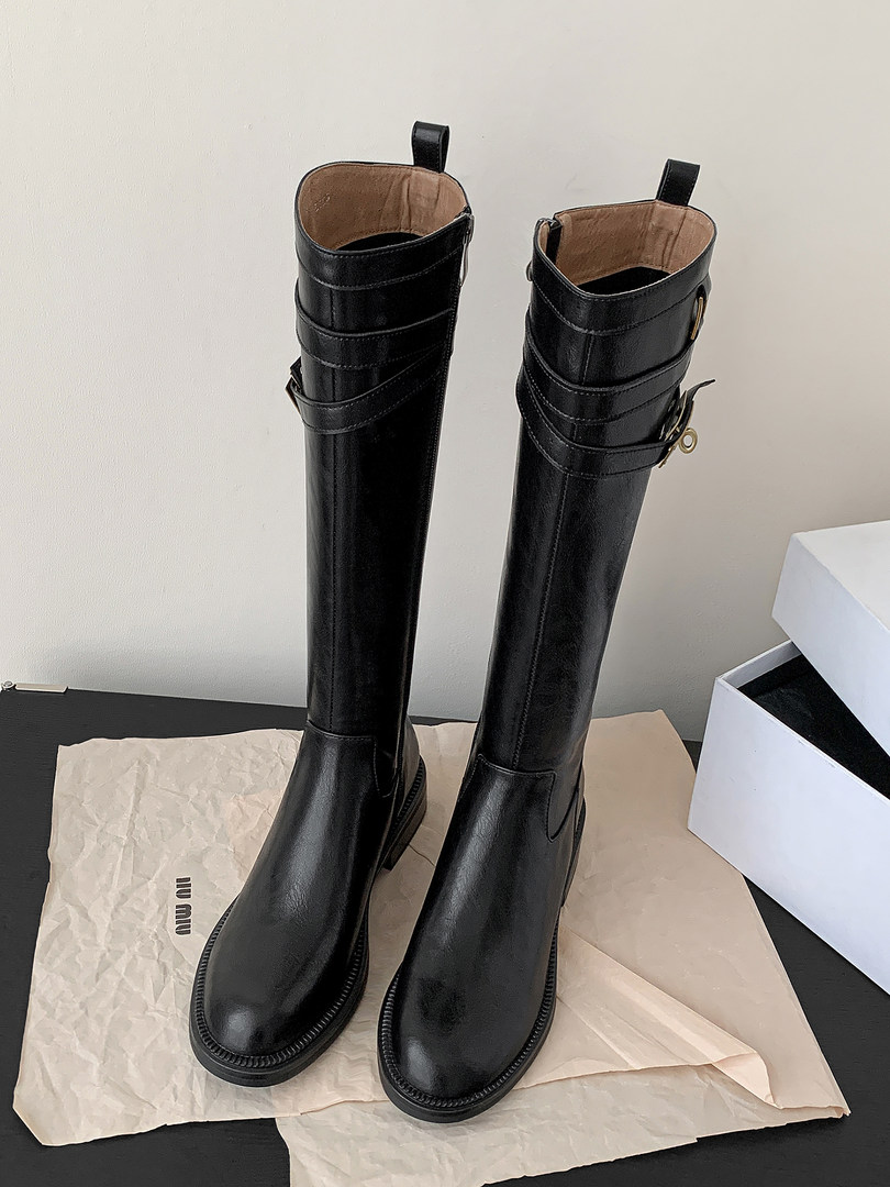 Black knee-high leather boots displayed upright on paper