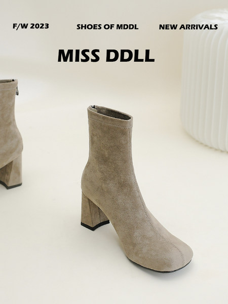 Beige suede ankle boots with block heels on a studio background
