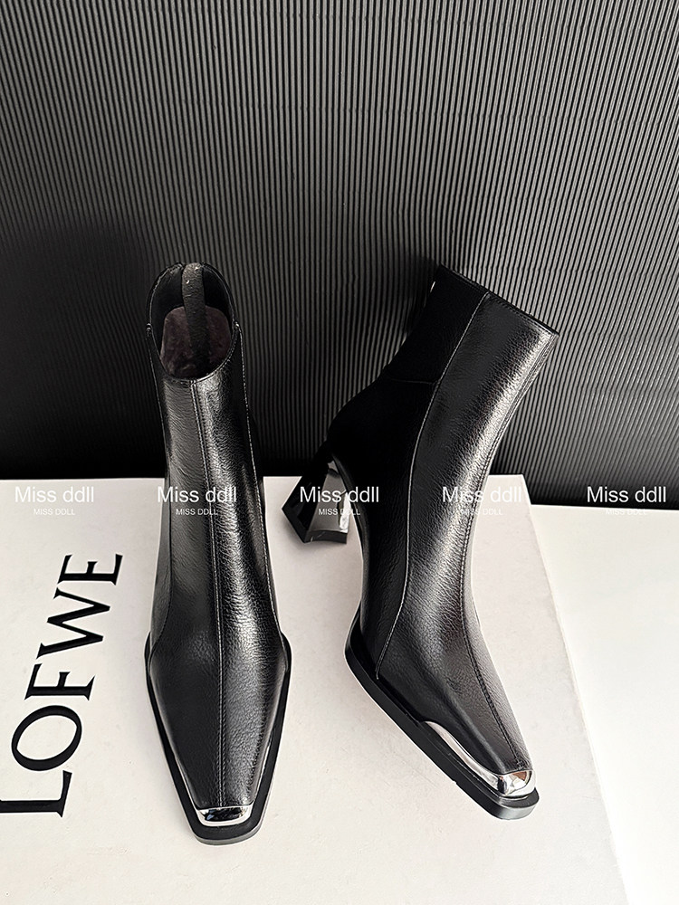 Black pointed-toe heeled ankle boots on a white surface