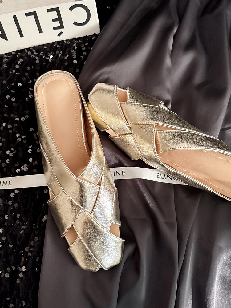 Metallic gold slip-on shoes laid on dark fabric