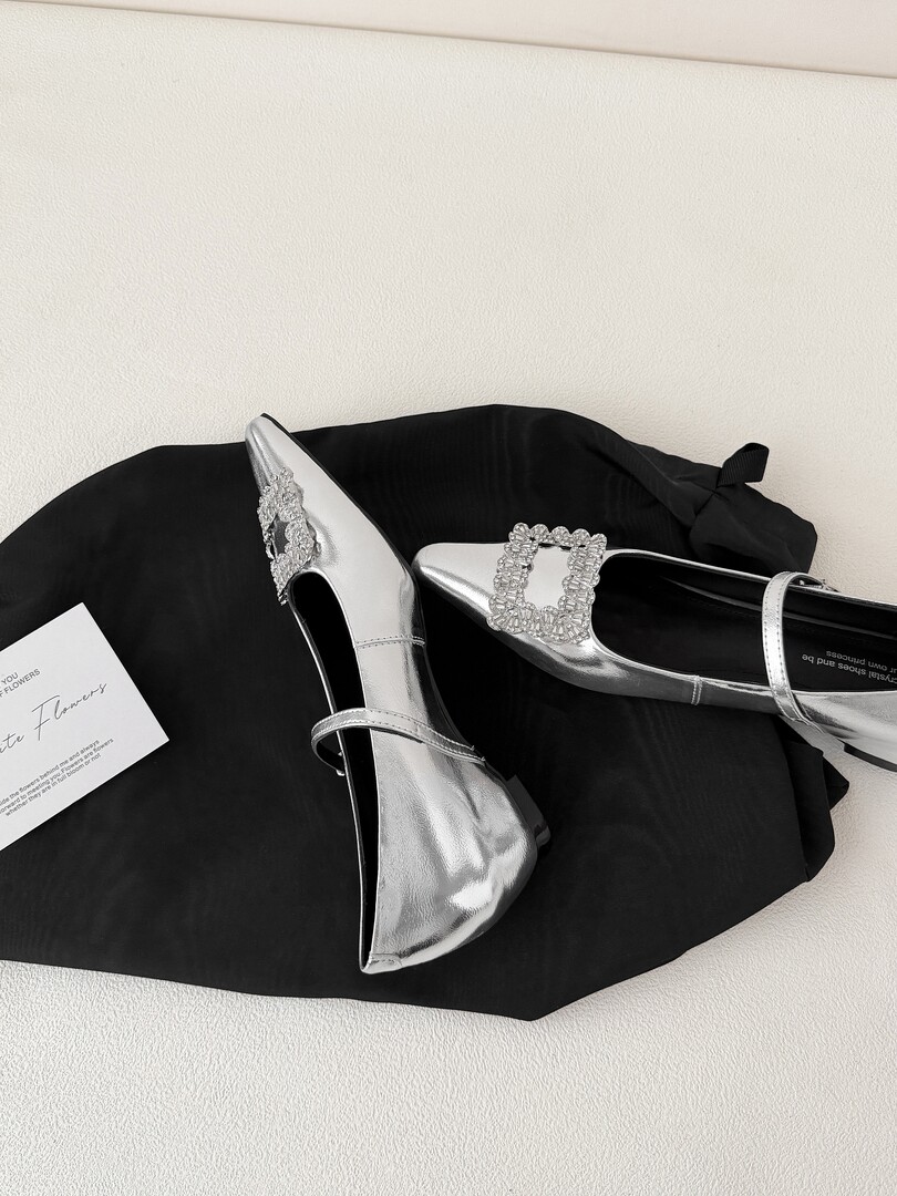 Silver pointed-toe slingback heels with crystal embellishments on a black background