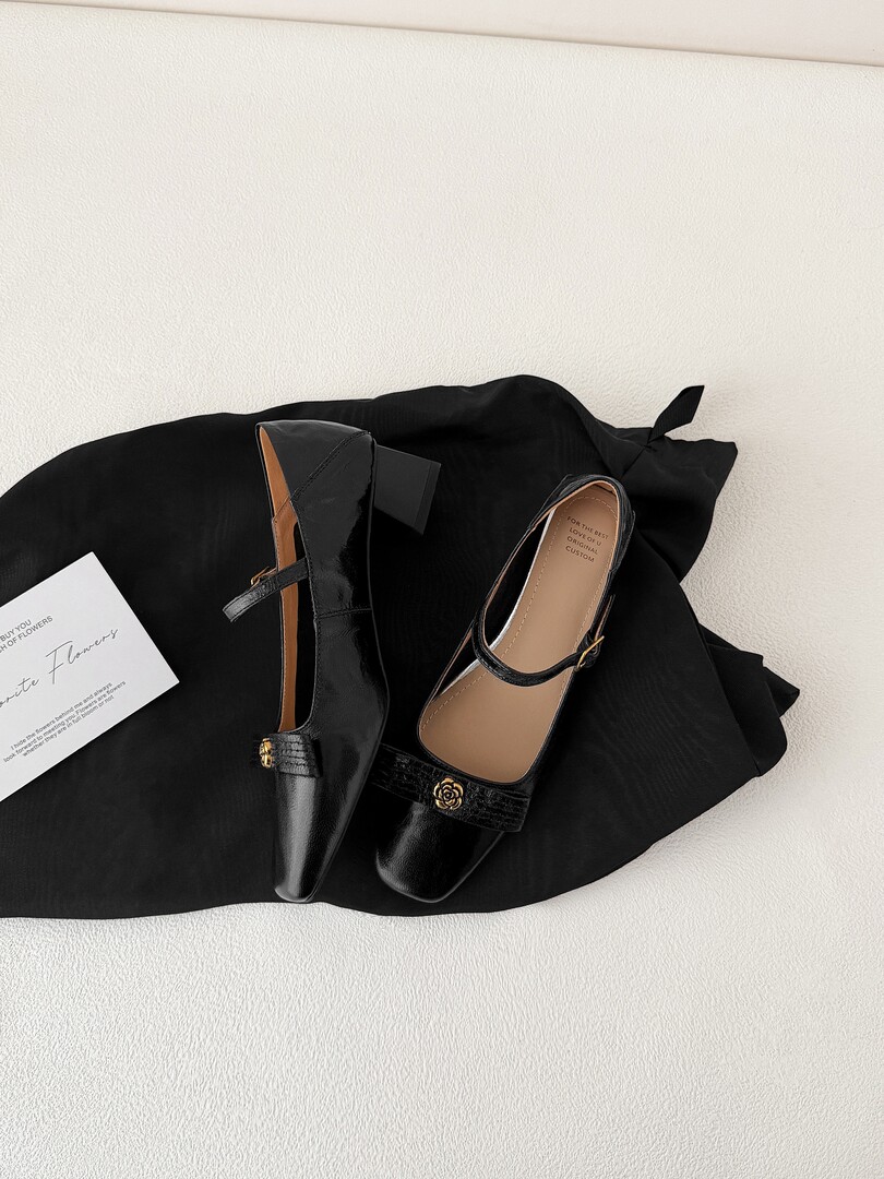 Black glossy Mary Jane flats displayed on black fabric