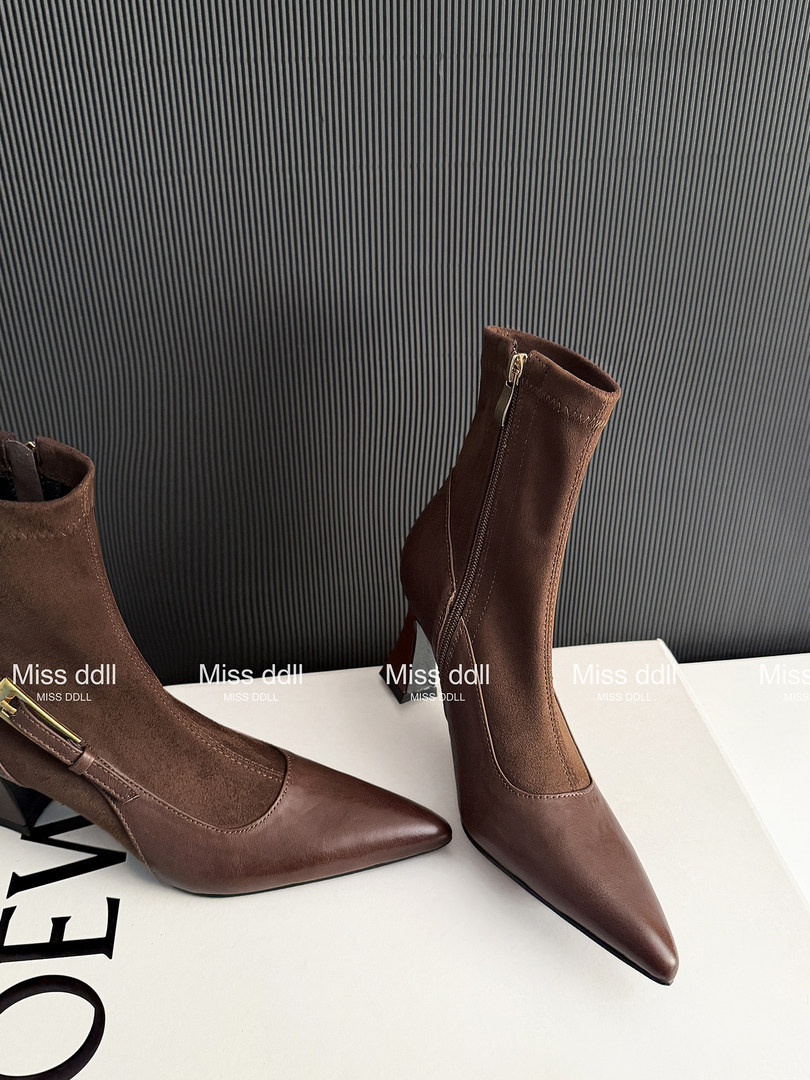 Brown pointed-toe ankle boots with side zippers on a display surface