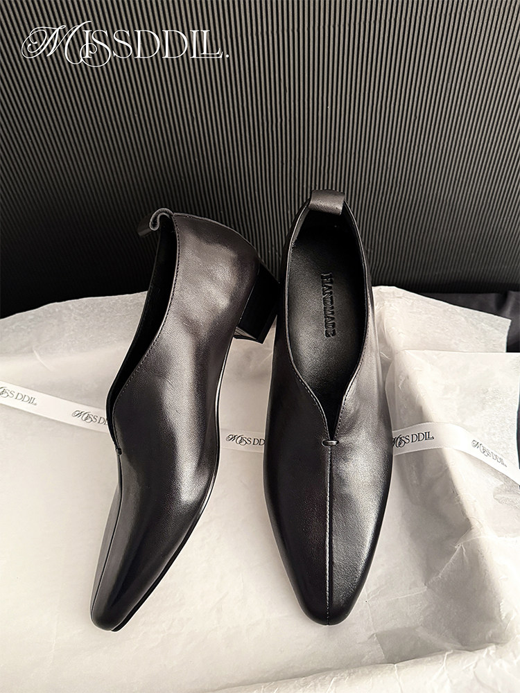 Black pointed-toe leather heeled shoes displayed on tissue paper