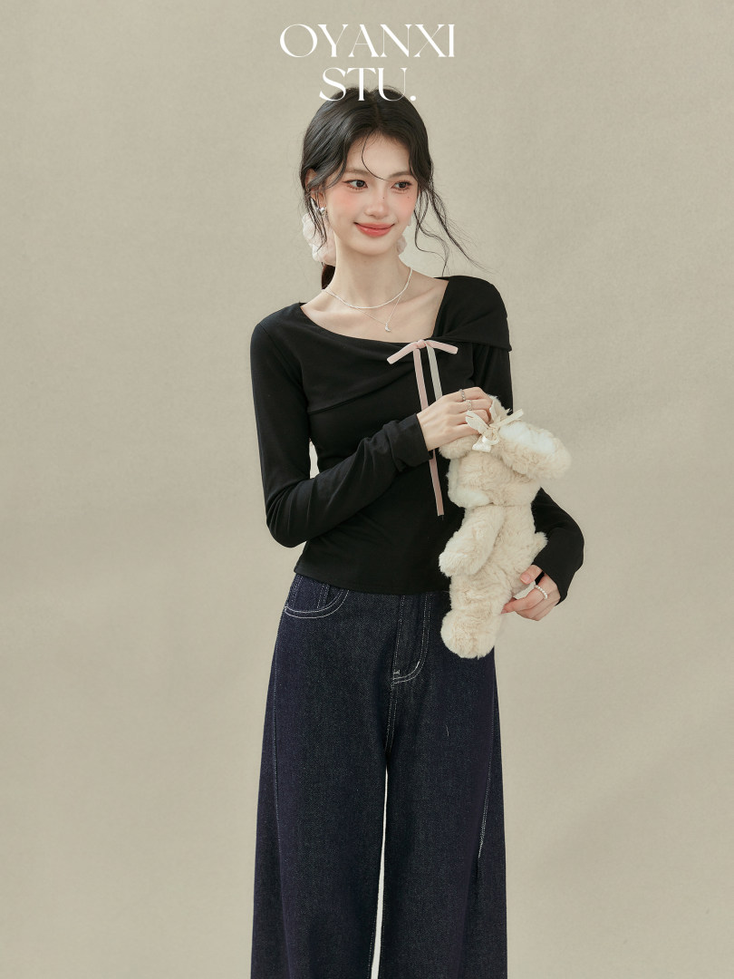 Model wearing a black long-sleeve top with wide-leg jeans
