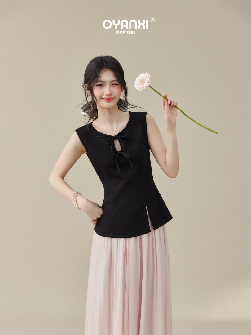 Model wearing a black sleeveless top with a pink pleated skirt