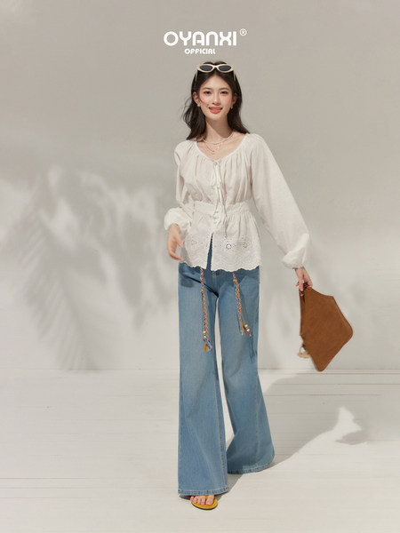 Model wearing a white blouse with wide-leg blue jeans and a brown clutch