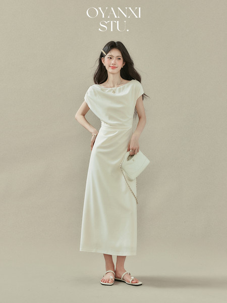 Model wearing a cream sleeveless midi dress with a small white handbag and sandals