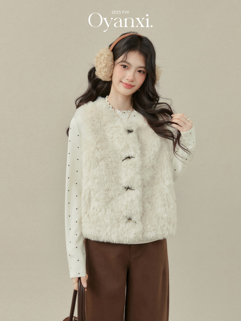 Model wearing a fluffy cream faux-fur vest with earmuffs and brown pants