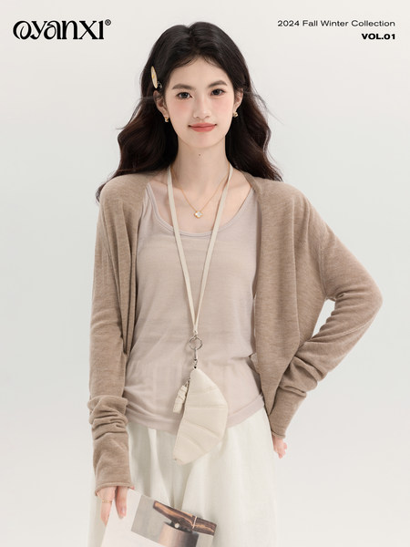 Fashion model wearing a beige layered knit outfit in a fall/winter collection photo