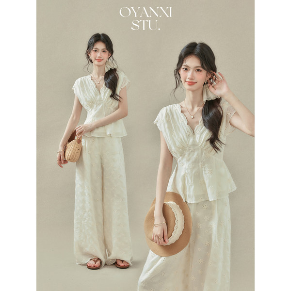 White lace two-piece outfit worn by a model with a straw hat and woven bag
