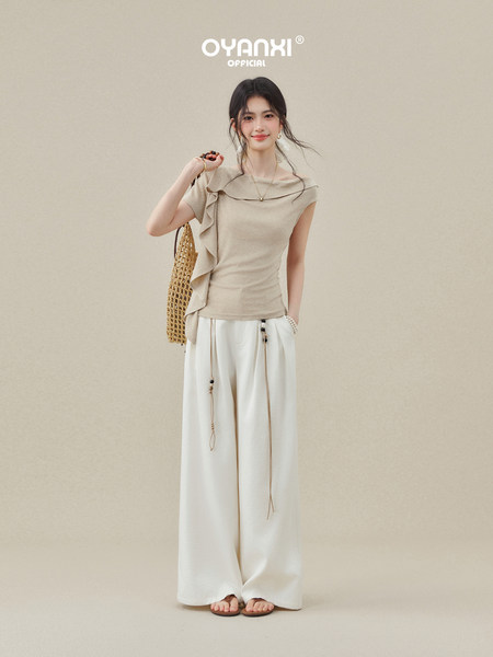 Beige off-shoulder top with white wide-leg pants worn by a model