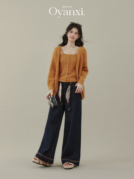 Woman modeling a mustard knit cardigan and top with wide-leg dark jeans