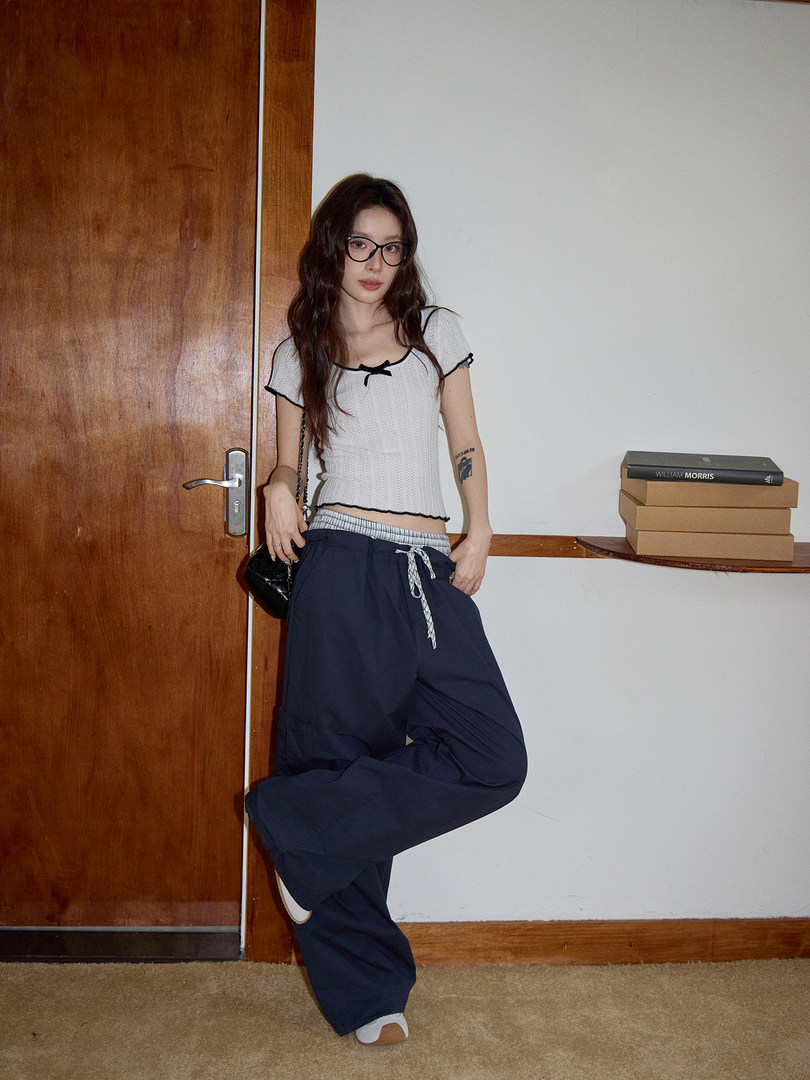 Model wearing a white knit short-sleeve top with navy wide-leg pants
