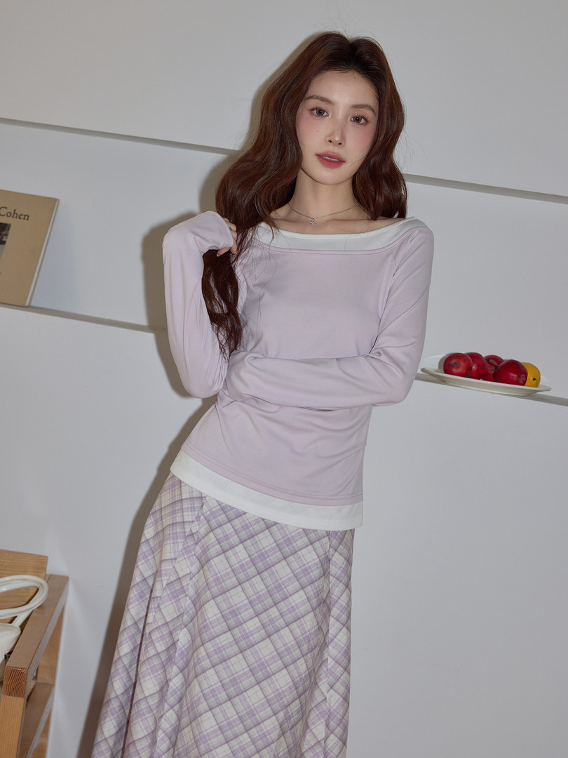 Model wearing a light pink long-sleeve top and plaid skirt