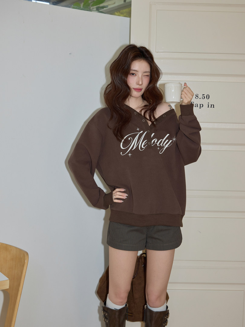 Model wearing a brown oversized graphic sweatshirt with shorts and boots