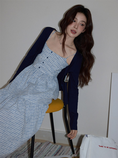 Model wearing a blue gingham dress with a dark cardigan