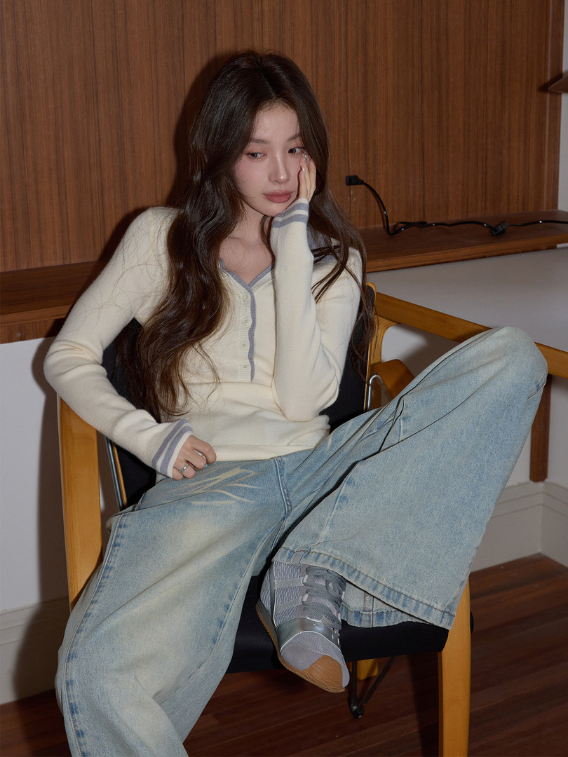 Model wearing a cream button-front cardigan with light wide-leg jeans and gray sneakers