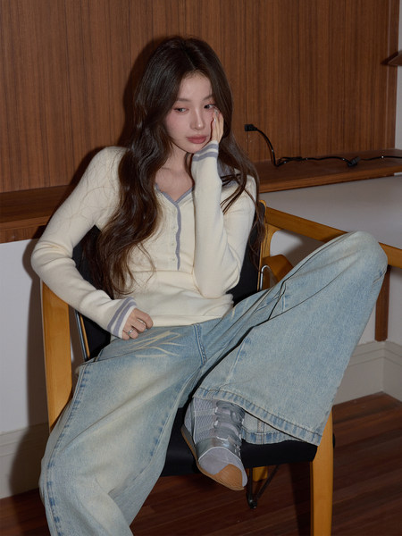 Model wearing a cream button-front cardigan with light wide-leg jeans and gray sneakers