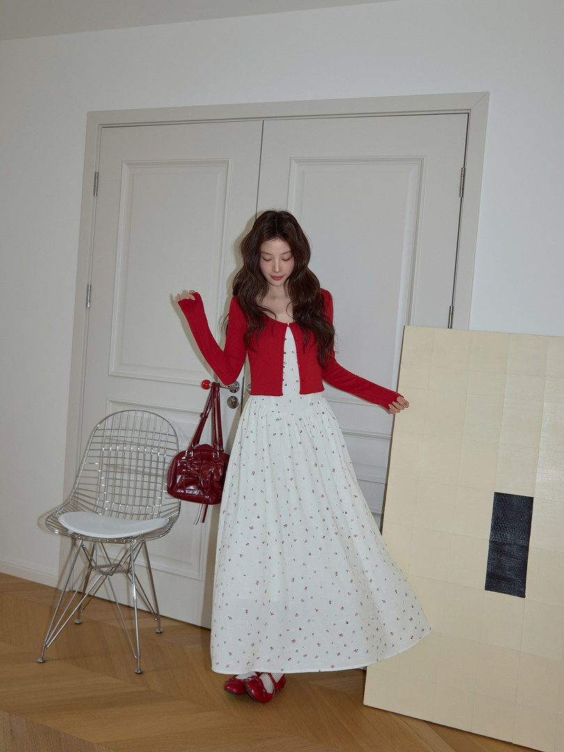 Model wearing a red cardigan over a white floral maxi dress with red shoes and handbag