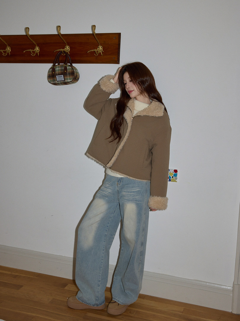 Woman modeling a brown shearling-lined jacket with light blue jeans