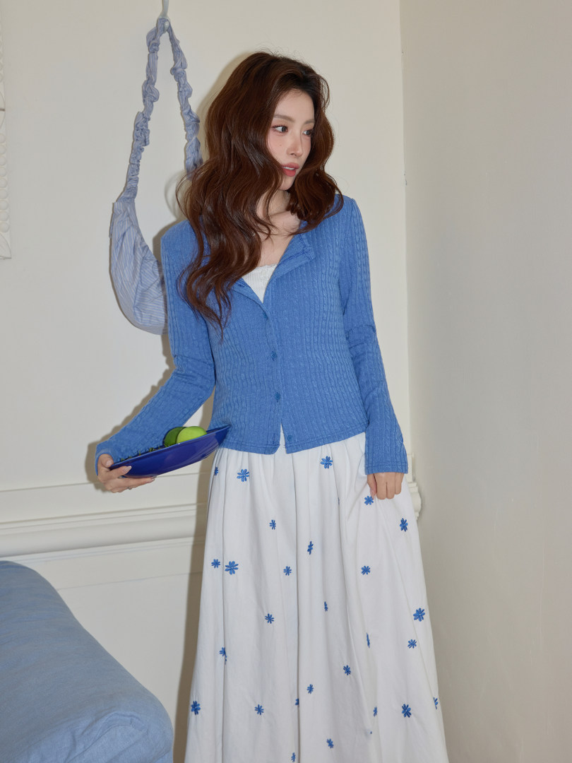 Model wearing a blue ribbed cardigan and a white floral skirt