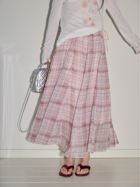 Person wearing a pink plaid maxi skirt with a white long-sleeve top and sandals