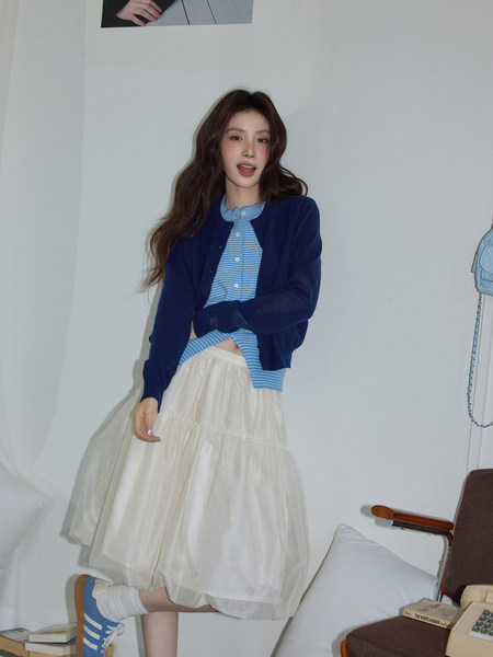 Woman modeling a navy cardigan over a blue striped top with a cream tulle skirt
