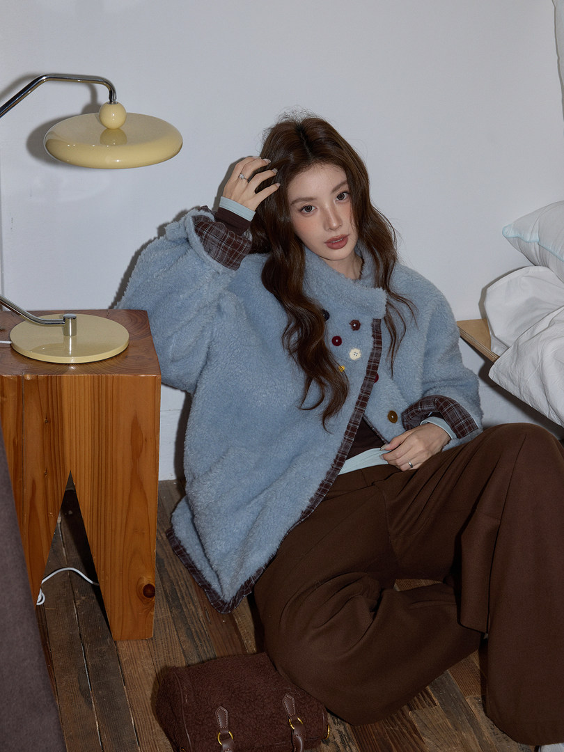 Model wearing a light blue fuzzy jacket with plaid trim and brown pants