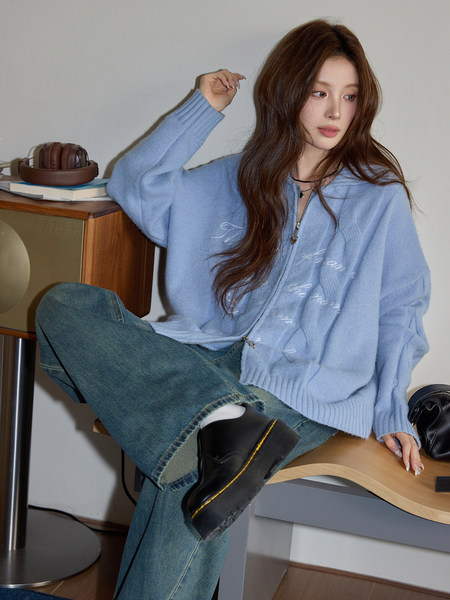 Model wearing a light blue zip-up knit sweater with jeans and black shoes