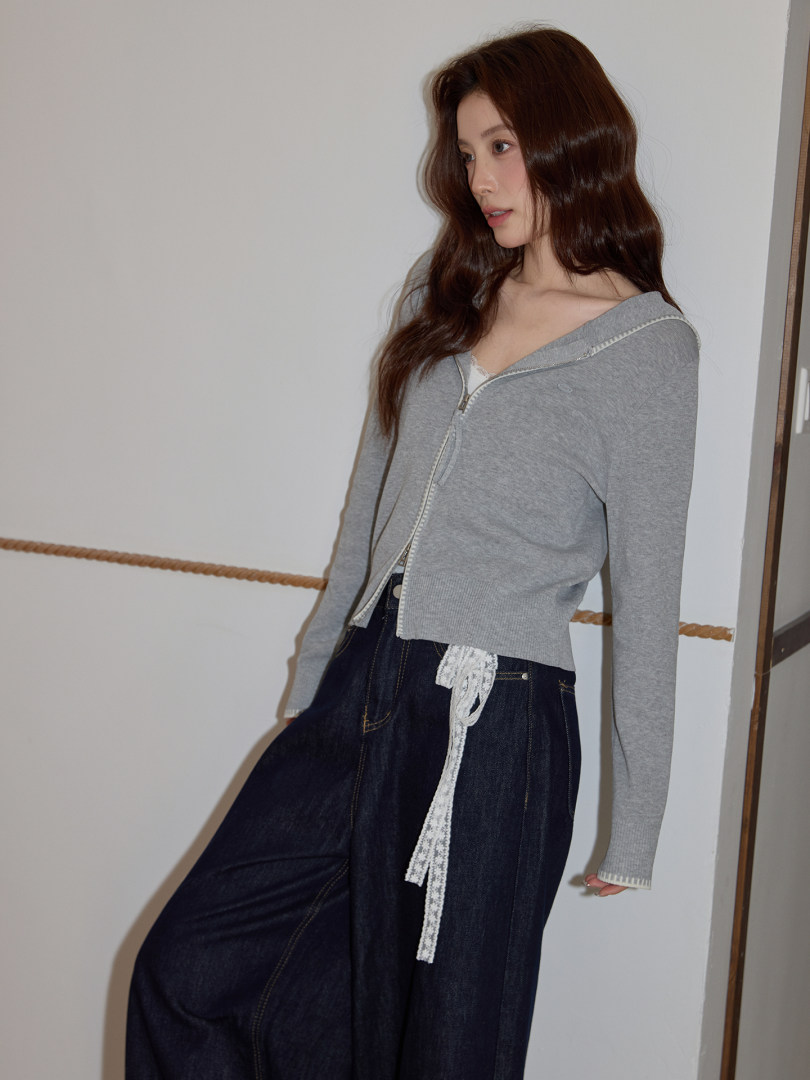 Model wearing a gray zip-front knit top with dark wide-leg pants
