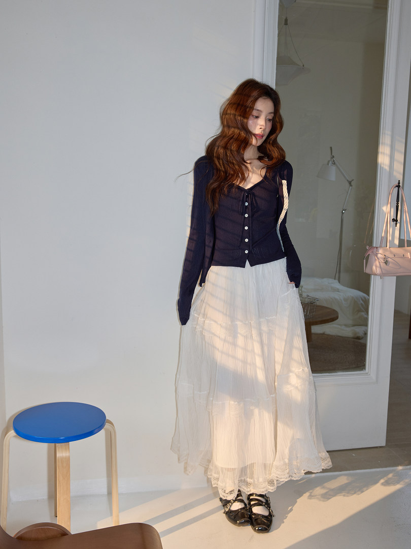 Model wearing a navy long-sleeve button-up top with a white tiered maxi skirt