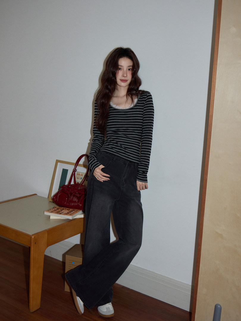 Model wearing a black-and-gray striped long-sleeve top with dark wide-leg jeans