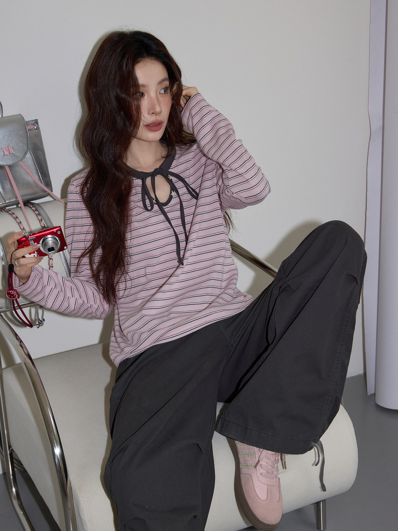 Woman wearing a pink striped long-sleeve top with black pants and pink sneakers