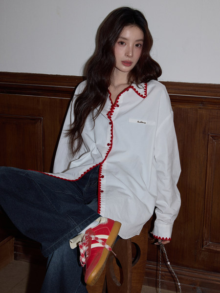 Model wearing a white shirt with red trim, dark jeans, and red sneakers