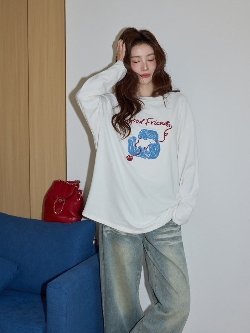 Model wearing a white graphic long-sleeve top with relaxed jeans