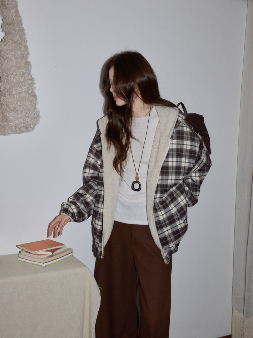 Model wearing a plaid sherpa-lined jacket with a white top and brown pants