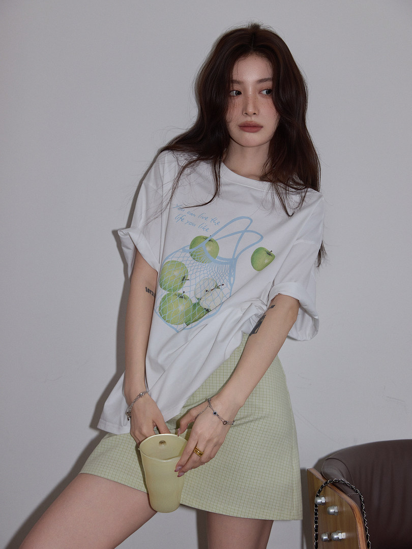 Model wearing a white graphic oversized T-shirt with a light green mini skirt