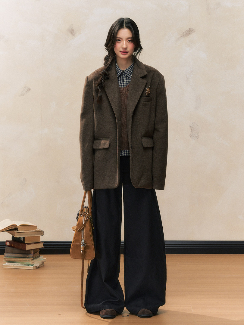 Model wearing a brown oversized blazer with wide-leg black trousers and a handbag