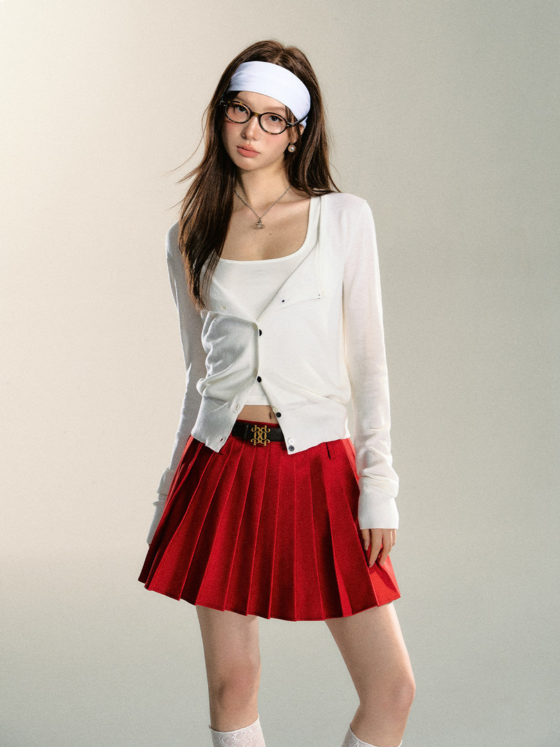 Model wearing a white cardigan and red pleated skirt with a headband