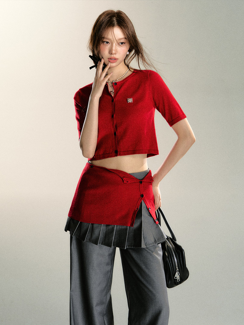 Model wearing a red cropped knit top with matching layered skirt over gray pants