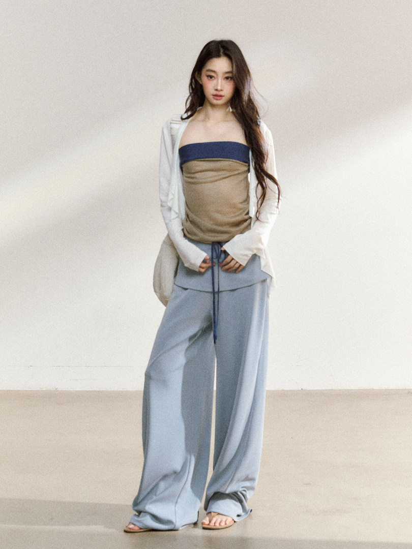 Model wearing a strapless two-tone top with light blue wide-leg pants and a white cardigan