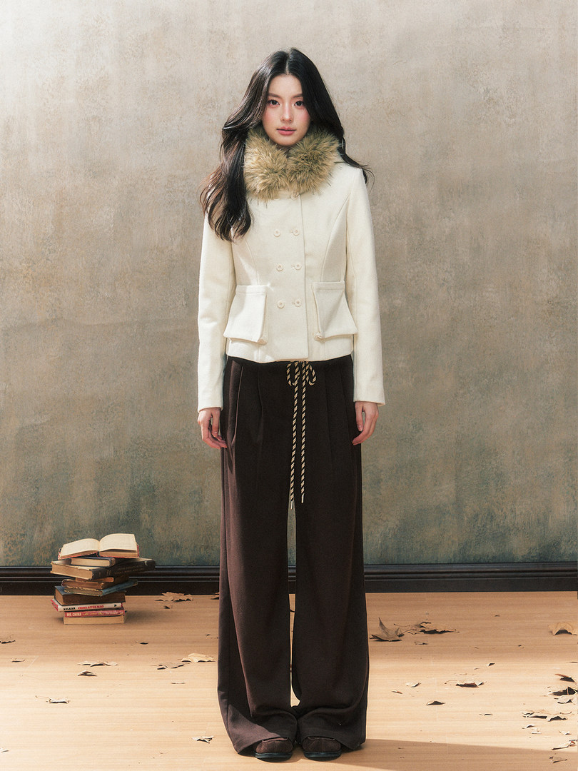 Model wearing a cream jacket with fur collar and wide-leg brown pants